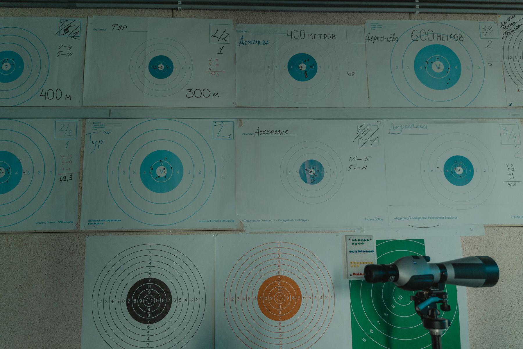Wall of scored paper targets with a spotting scope at a shooting range